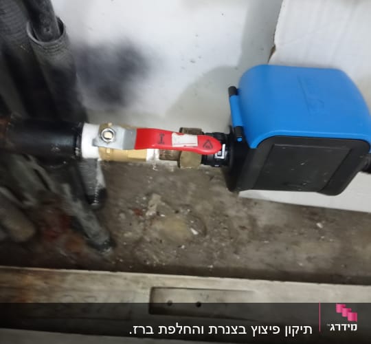 שסתום מים עם ידית אדומה ומכשיר כחול